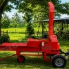 Red Massive Chaff Cutter mounted on a trailer in a rural farm setting with green grass and trees edges and a shed in the background.