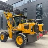 Yellow wheel loader with a raised front bucket parked outside a dark modern building angle view, industrial equipment ready for work.