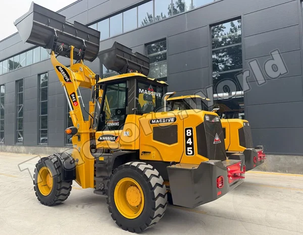 Yellow wheel loader with a raised front bucket parked outside a dark modern building angle view, industrial equipment ready for work.