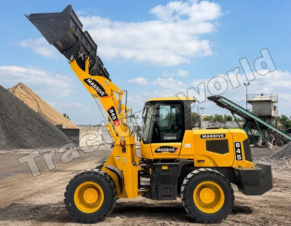 Yellow front-end loader with raised bucket loading gravel at a quarry, clear blue sky in the background and a conveyor belt nearby.